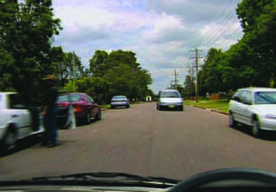 Exmaple photo of narrow road with a person with car door open on the left and an oncoming vehicle