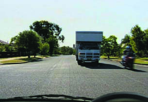 Motorcycle travelling towards you through an intersection as a truck waits to turn right